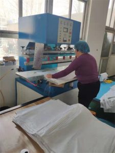 Workers are operating the high-frequency machine to heat-press body pouch